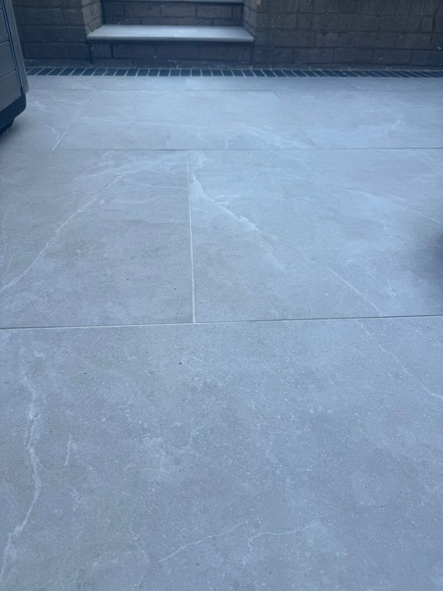 Grey porcelain patio with charcoal-slate border and channel drainage installed by Prostone — view 2