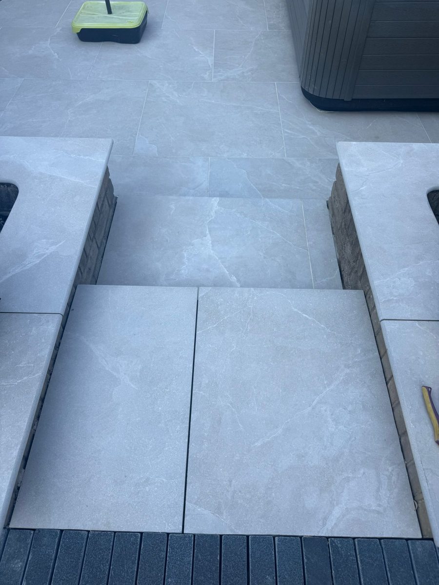 Grey porcelain patio with charcoal-slate border and channel drainage installed by Prostone — view 5
