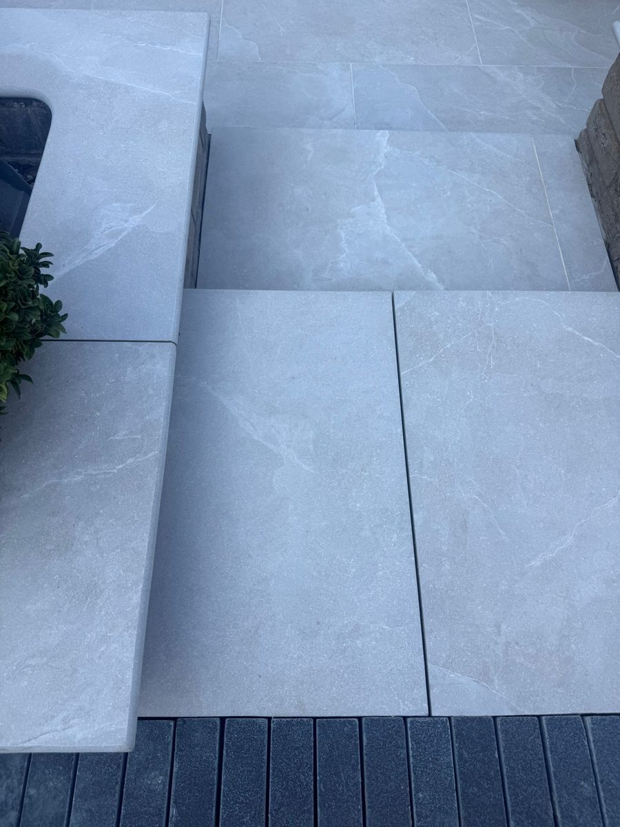 Grey porcelain patio with charcoal-slate border and channel drainage installed by Prostone — view 6